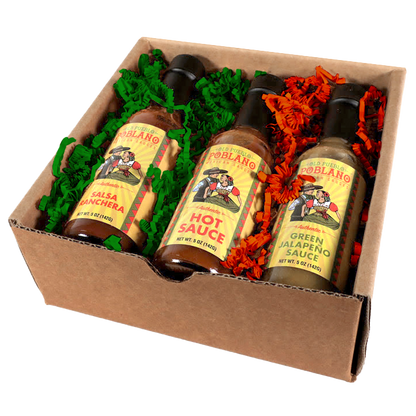 Three bottles of Poblano brand sauce in a cardboard box with decorative paper.