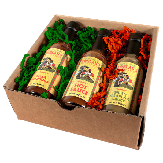 Three bottles of Poblano brand sauce in a cardboard box with decorative paper.